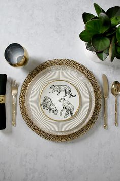 a plate with two bears on it next to utensils and a potted plant