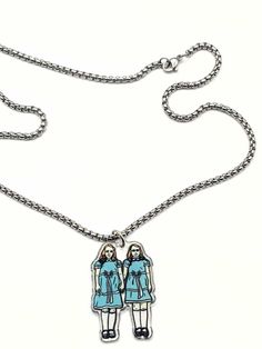 a necklace with two people on it and one is wearing a blue coat, the other has