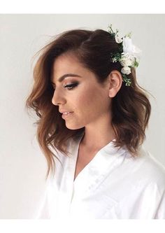 a woman wearing a white robe with flowers in her hair