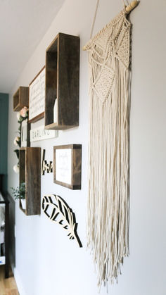 the wall is decorated with wooden boxes and macrame art hanging from it's sides