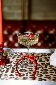 a table topped with a wine glass filled with liquid next to a red candle holder