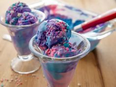 two glasses filled with ice cream and sprinkles on top of a wooden table