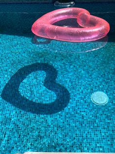 an inflatable heart floating on top of a pool next to a swimming ring