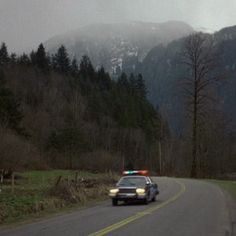 a police car driving down the road with mountains in the background