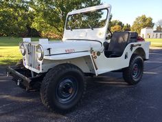 an old white jeep parked in a parking lot