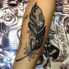 a woman's arm with a tattoo on it and a feather in the middle