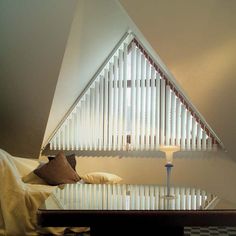 a bed sitting under a triangular shaped window