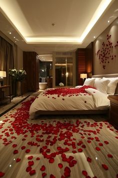 a bed with rose petals on the floor in a room that looks like it has been decorated