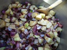 chopped red onions and apples in a silver bowl with a wooden spoon on the side