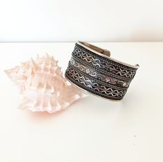 A wide, rich decorated by engraved motifs, vintage silver tone metal, probably alpaca, open cuff bracelet, made in the '80s.  The bracelet reminds ancient Greek or Romaic jewelry and can be worn by almost anyone, as it suits women and men, young or less young. Please remember that it is not a new item, so there can be time signs on it. It is a second hand, antique bracelet, in very good vintage condition. Bohemian Metal Bracelets With Antique Finish, Bohemian Adjustable Cuff Bracelet With Antique Finish, Bohemian Antique Silver Bangle With Oxidized Finish, Bohemian Metal Bracelet With Antique Finish, Adjustable Bohemian Cuff Bracelet With Antique Finish, Silver Oxidized Bangle For Festival, Silver Bangle With Oxidized Finish For Festival, Bohemian Silver Metal Cuff Bracelet, Silver Metal Bohemian Cuff Bracelet