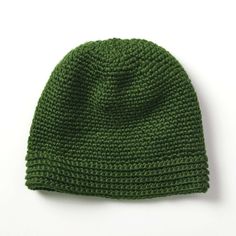 a green knitted hat sitting on top of a white table