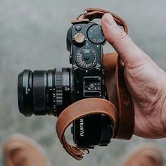 a person holding a camera in their hand with the strap around it's body