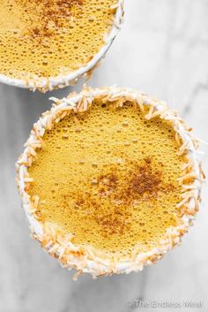 two pies with white frosting and sprinkles on them sitting next to each other