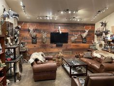 a living room filled with lots of furniture and deer heads on the wall behind it