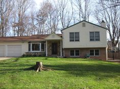 a large house sitting in the middle of a lush green field next to a tree