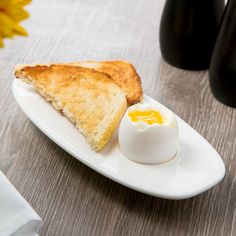 two pieces of toast and an egg on a white plate next to black vases