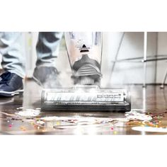 a person using a vacuum cleaner on the floor with confetti scattered around it