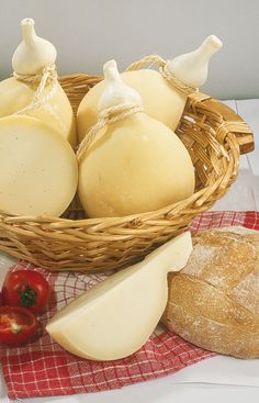 a basket filled with cheese next to bread and tomatoes