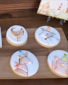 several decorated cookies with animals on them sitting on a wooden table next to a book