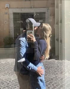 a man and woman taking a selfie in front of a building with their cell phone