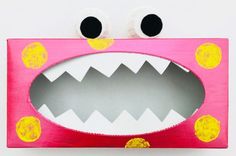 a pink box with googly eyes and mouth painted on the inside is decorated like a monster