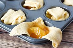 an open muffin tin filled with cupcake batter and apple filling in the middle