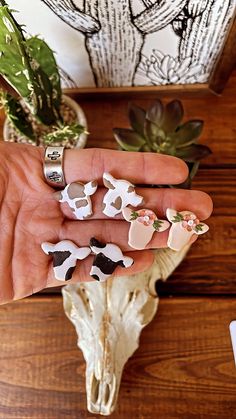 a person's hand holding several pieces of animal magnets in front of a cow skull and succulent plant