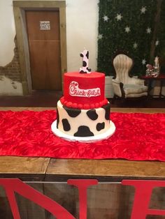 a cake decorated with a coca - cola theme is on a red tablecloth in front of a chair