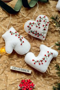 three ornaments are sitting on a table next to some christmas tree branches and decorations with the word december written in them