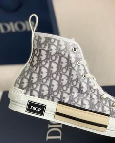 Reimagine classic high-top style with these sneakers, drawing inspiration from the iconic Dior B23 and Converse's timeless appeal. Featuring a clean white base with a grey Dior Oblique-inspired jacquard overlay and a transparent panel showcasing the intricate pattern, these shoes offer a modern and sophisticated look. The contrasting black stripe detail on the white rubber sole adds a sporty edge. Sneakers Drawing, Pretty Shoes Sneakers, Dior Oblique, Sneakers Addict, Bottega Veneta Shoulder Bag, Loafer Sneakers, Dior Shoes, Outfit Maker, Drawing Inspiration