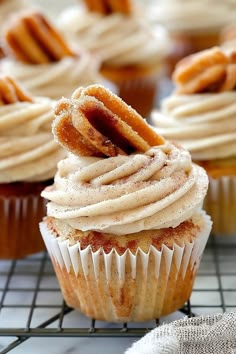 cupcakes with frosting and pretzels on top sitting on a cooling rack