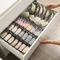 a drawer is open with many pairs of shoes in it and someone's hand reaching for them