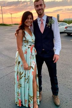 a man and woman standing next to each other in front of a parking lot at sunset