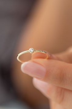 a close up of a person holding a gold ring with a diamond on the side