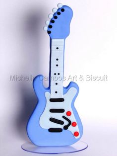 a blue and white guitar shaped cake on top of a plate with a red dot