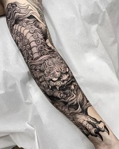 a man's arm covered in black and white ink with an intricate dragon tattoo on it