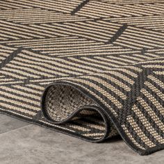 an area rug with black and beige designs on it, laying on the floor next to a tile floor