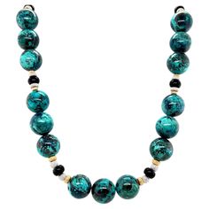 This stunning necklace features beautifully variegated chrysocolla quartz beads combined with black onyx and 18k gold spacers. The 12mm round chrysocolla beads, with their striking patterns of rich turquoise, teal, and indigo blues, are accented perfectly by smaller onyx beads. 18k white and yellow gold stardust spacers add elegance and refinement to the natural, organic feel of the chrysocolla. Hand strung on silk thread with a beautiful satin-finished ball clasp, the necklace measures 21 inche Elegant Turquoise Chrysocolla Necklace, Elegant Turquoise Necklace With Polished Beads, Vintage Beads Necklace, Quartz Beads, Onyx Bead, Stunning Necklace, Silk Thread, Natural Organic, Gold Accents