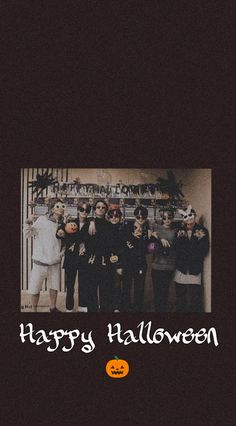 a group of people standing next to each other in front of a wall with the words happy halloween written on it