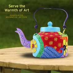 a colorful tea kettle sitting on top of a wooden table