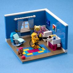 a toy house with furniture and toys on the floor in front of a blue wall