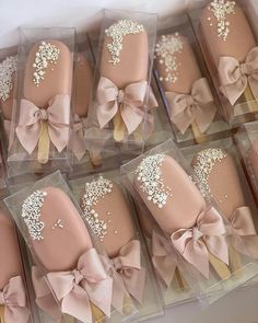 there are many pink and gold decorated cookies in plastic boxes with bows on them,