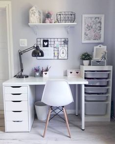 a white desk topped with lots of drawers and a chair under a shelf filled with pictures