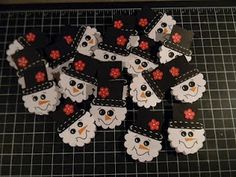 several snowmen with black hats and red flowers are on a cutting board next to some scissors