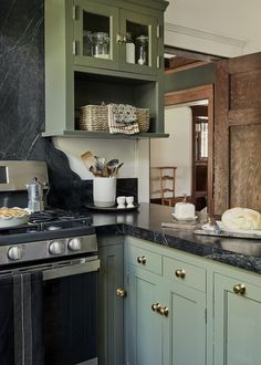 a kitchen with green cabinets and marble counter tops