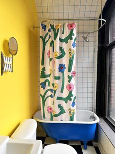 a bathroom with yellow walls and black and white checkered flooring, a blue bathtub next to a window