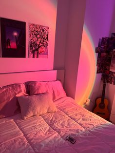 a bed with pink sheets and pillows in a room that has pictures on the wall