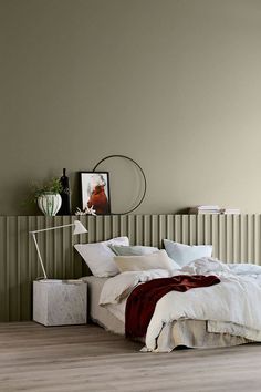 a bed with white linens and pillows in a bedroom next to a wooden floor