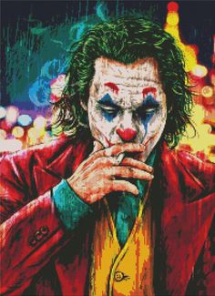 the joker cross stitch pattern in red and yellow with his hands on his face, looking down