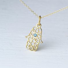 Tiny Hamsa pendant in solid gold with a tiny natural blue diamond in the centre.  - length: 0.6 inches / 1.5 cm   - width 0.4 inches / 1.1 cm Available in 9k, 14k and 18k yellow, white and rose gold.  The pendant is available with a solid gold chain or without a chain (pendant only). It will be a 9k solid gold chain for the 9k pendant, a 14k solid gold chain for the 14k pendant and a 18k solid gold chain for the 18k pendant.   Beautiful filigree pendant, Fatima hand with tiny evil eye. Protection Charm, also available without the diamond. For other colors please contact me. Perfect gift for Valentine, Mother's Day or any other special occasion. Blue Gemstone Jewelry In Recycled Gold, Spiritual Yellow Gold Sterling Silver Birthstone Necklace, Blue Recycled Gold Jewelry For Anniversary, Elegant Blue Gold-plated Charm Necklace, Anniversary Blue Recycled Gold Jewelry, Blue Birthstone Necklace With 14k Gold Round Pendant, Blue 14k Gold Necklace With Charms, Delicate 14k Gold Blue Jewelry, Yellow Gold Blue Topaz Jewelry Gift